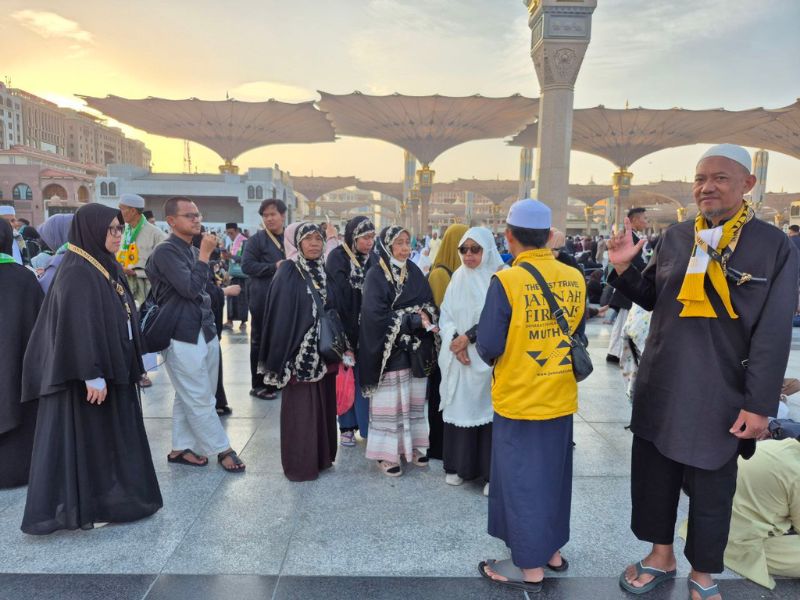 Jamaah Jannah Firdaus berada di Madinah dekat payung Masjid Nabawi dan diarahkan oleh pembimbing umroh